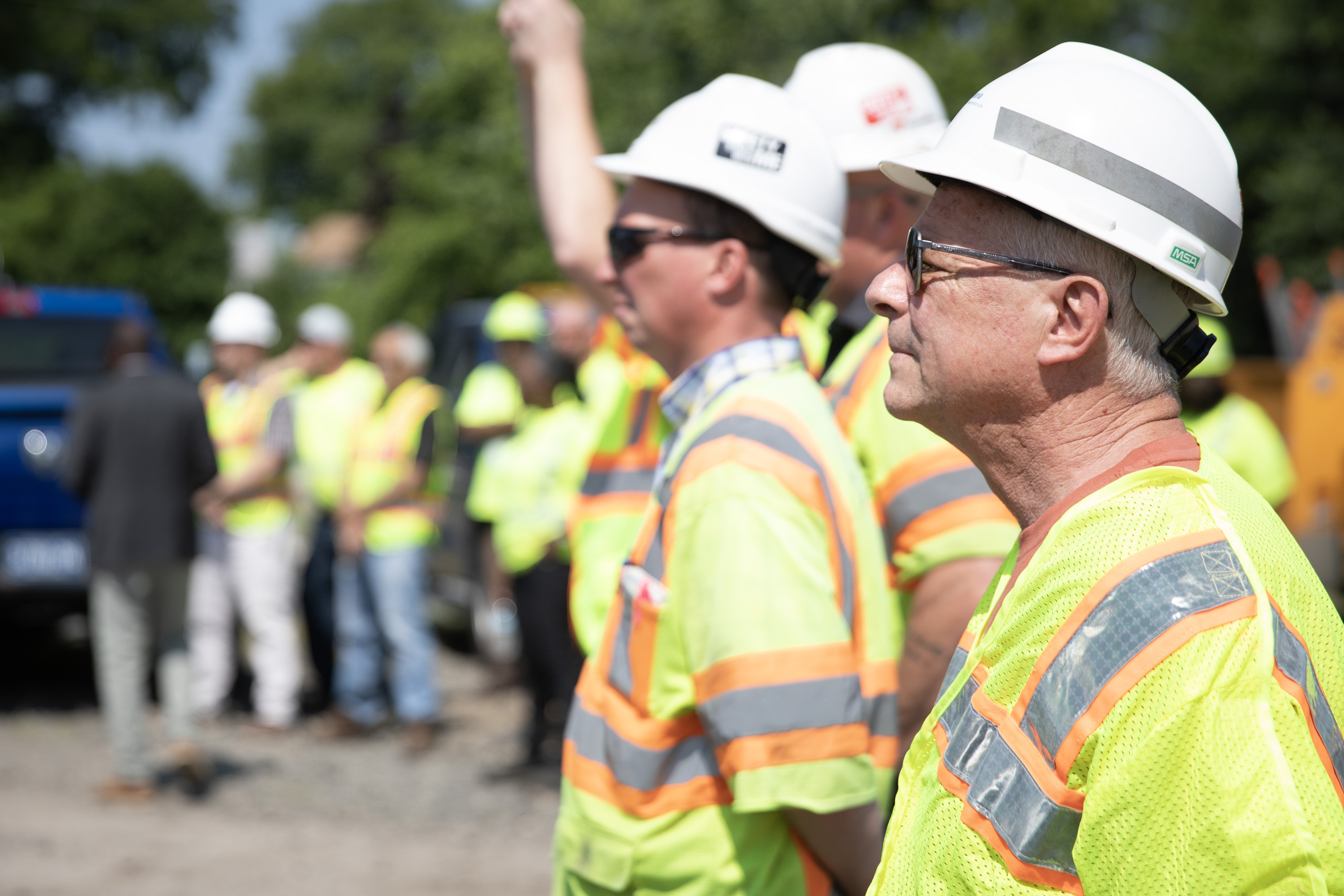 Workers with white hard hats and yellow safety vests standing in line during a training